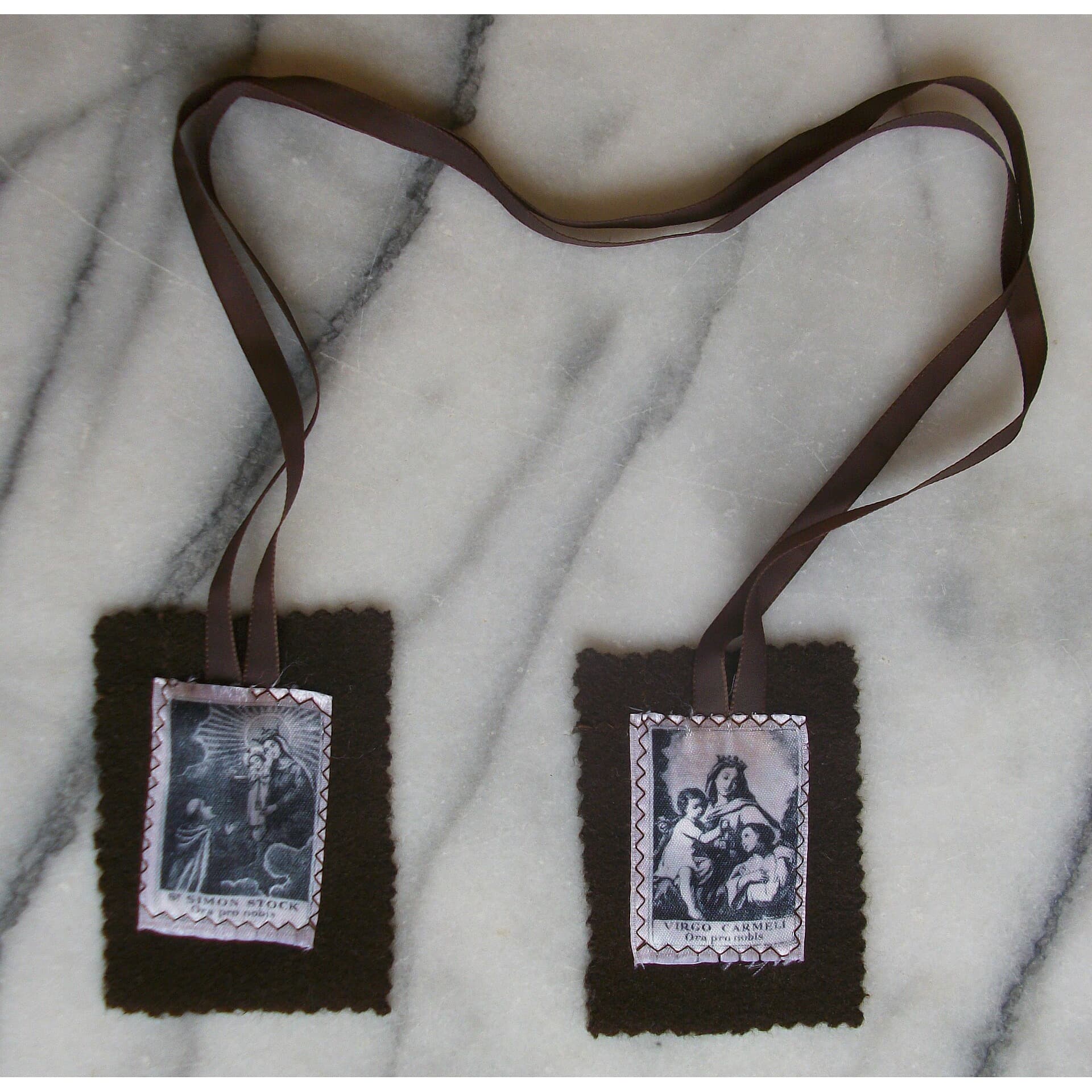 Brown felt scapular with two devotional image panels on a marble surface